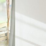 光が差す窓辺に本が重ねて置いてある写真